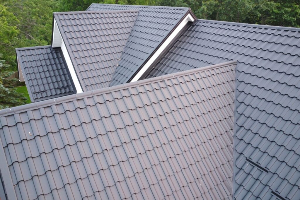 Aerial view of multiple intersecting sections of a dark metal tile roof, highlighting the smooth and sleek design.