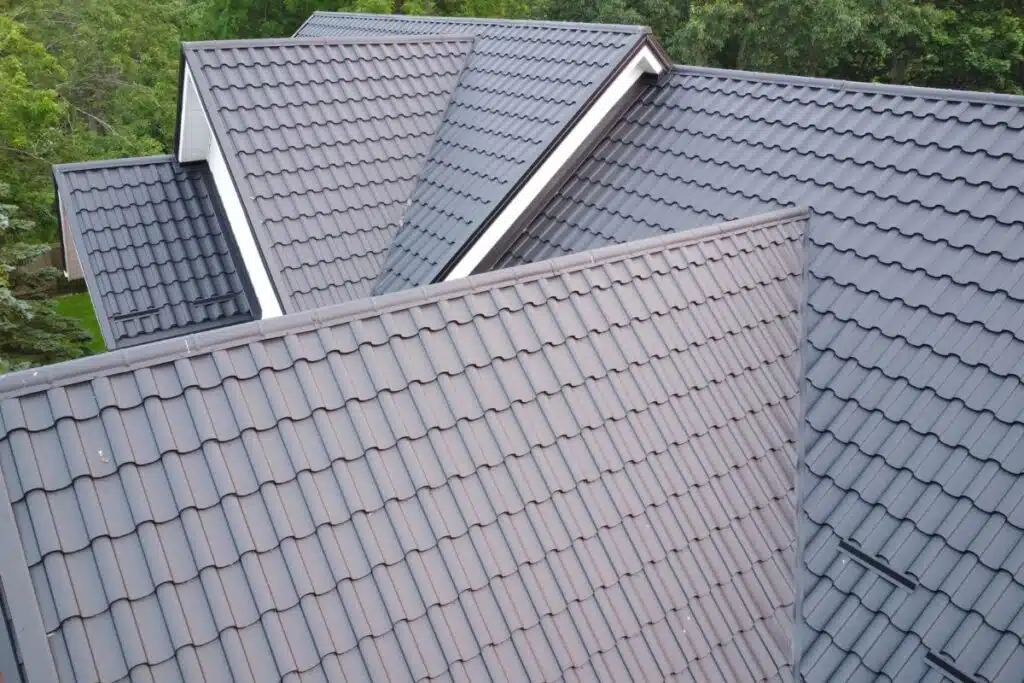 Aerial view of multiple intersecting sections of a dark metal tile roof, highlighting the smooth and sleek design.