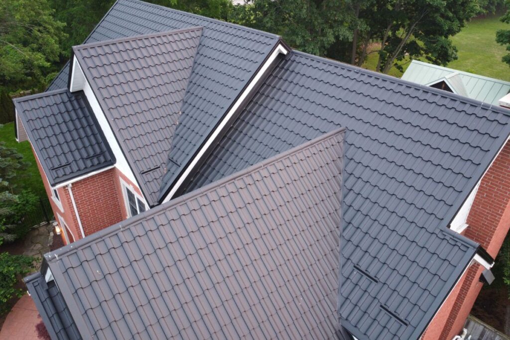Multiple intersecting roofs with a dark metal tile covering, showcasing an intricate roof design.