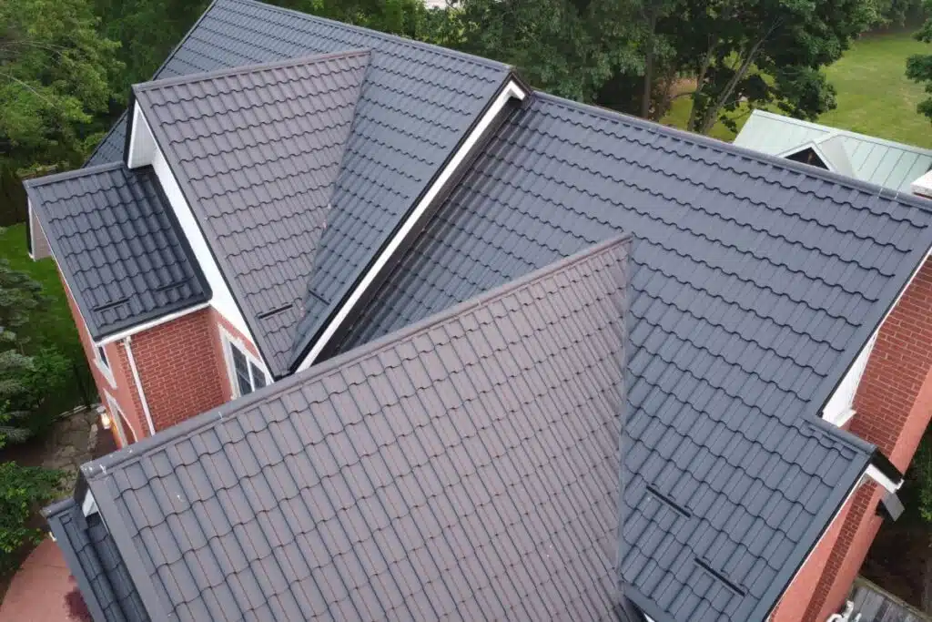 Multiple intersecting roofs with a dark metal tile covering, showcasing an intricate roof design.