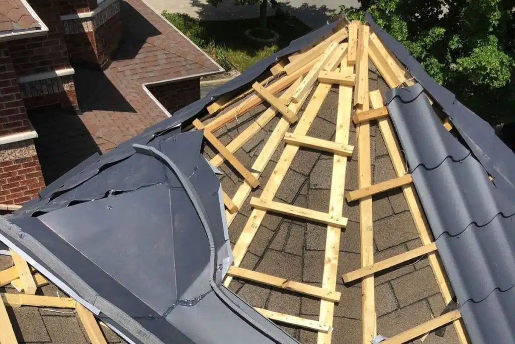 View of a roof in the process of installation, with wooden battens supporting the dark gray metal panels.