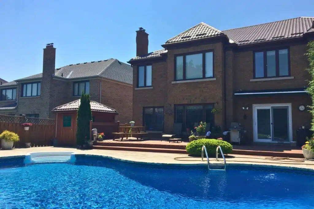 Beautiful home in Richmond Hill with a pool and a brown metal roof, featuring a wooden deck and lush greenery.