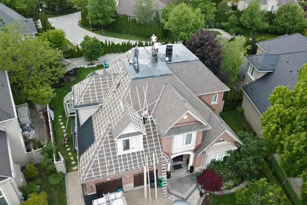 Roof in progress with workers installing the base layer, preparing the structure for the upcoming metal roof installation in North York.