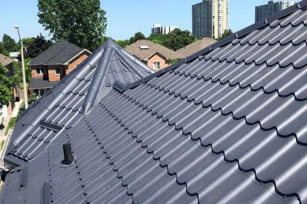 Textured metal roof with ventilation pipes, installed on a residential building in Hamilton, with surrounding suburban homes.