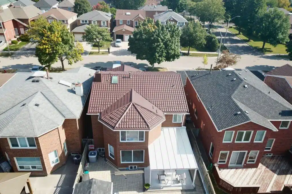 Aerial view of a finished brown metal roof with a skylight, surrounded by neighboring homes and showcasing its sleek design.