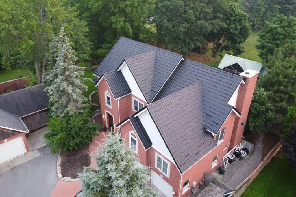 A bird's-eye view of a large residential property showcasing a beautifully installed black metal tile roof with neat lines.