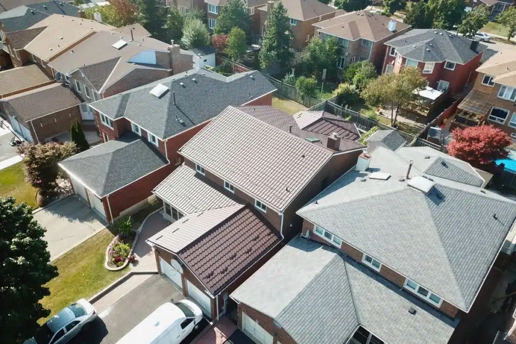 Aerial view showing a newly installed brown metal roof, contrasting with neighboring shingle roofs on the residential property.