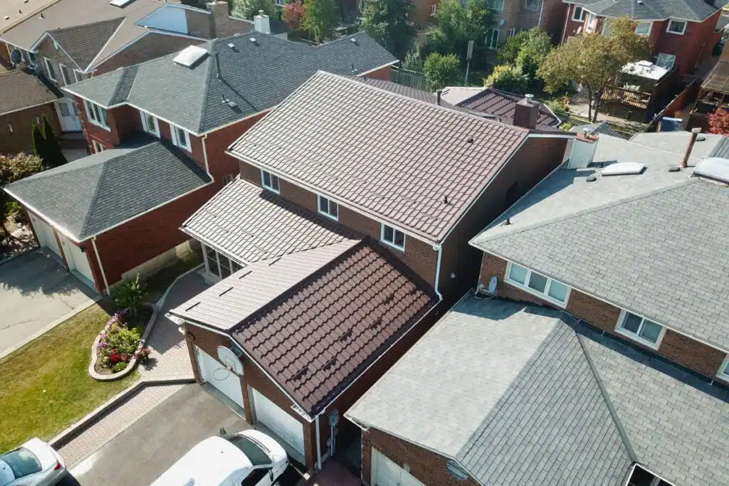 Aerial view of residential roofs with newly installed metal roofing tiles and surrounding houses.