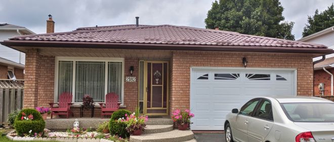 Red Tiled Roof with Brick Exterior and Garden Front view of a house with a red tiled roof, brick exterior, and well-maintained garden.