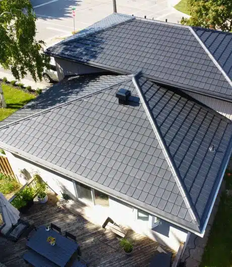 Aerial view of a house with a sleek, dark metal roof and a wooden deck.