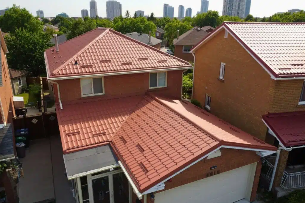 Two-story red brick house with a red Monterrey metal roof, featuring a covered front entrance, white-framed windows, and a double garage.