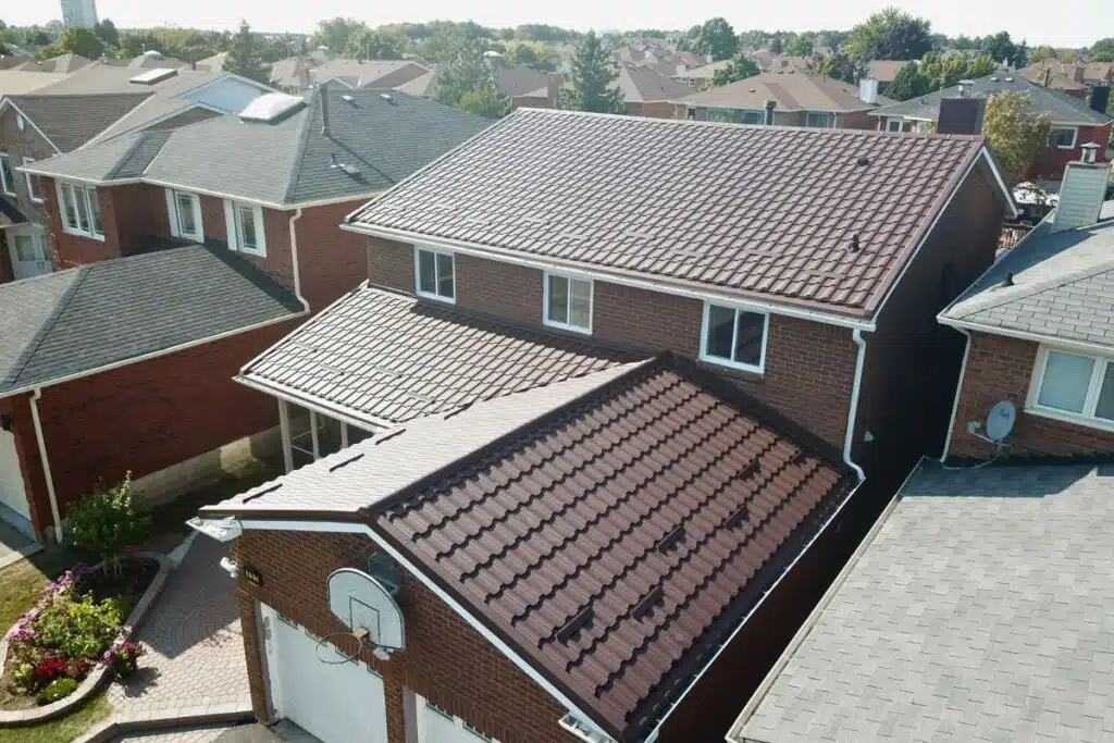 Adamante Metal Roof Installation – Durable and Stylish Roofing Two-story brick house with a brown Adamante metal roof, featuring a basketball hoop and surrounded by a neighborhood of similar homes.