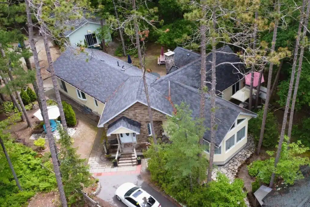 Dark Gray Shingle Roof with Stone Pathway and Greenery Top-down view of a home with a dark gray shingle roof, surrounded by trees and a stone pathway.