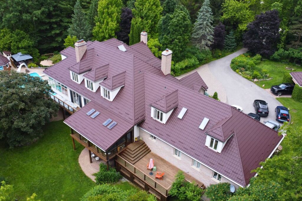 Large house with a chocolate brown metal tile roof, skylights, and a deck.