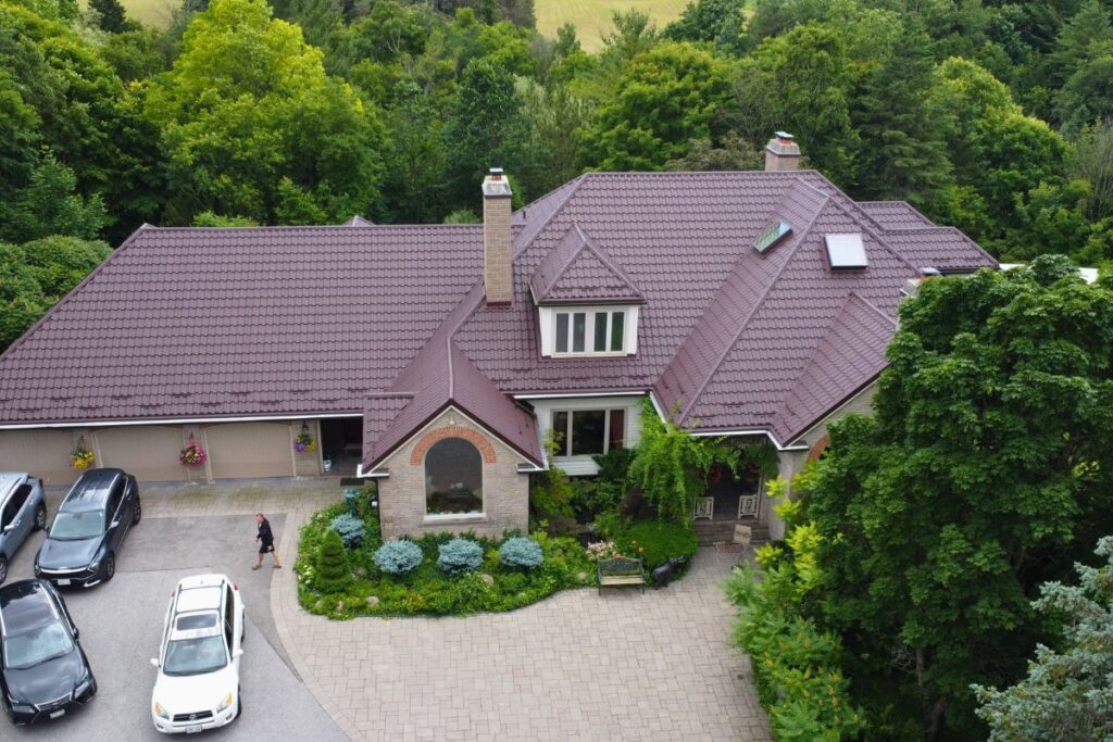 Elegant house with chocolate brown metal roof surrounded by lush greenery.