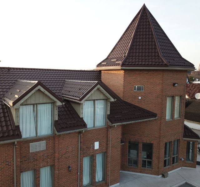 Close-up of a brick commercial building with brown metal tile roofing.