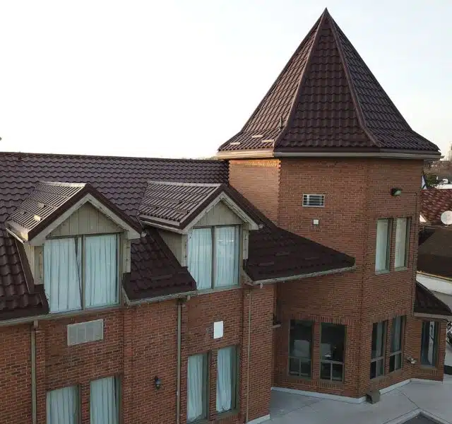Close-up of a brick commercial building with brown metal tile roofing.