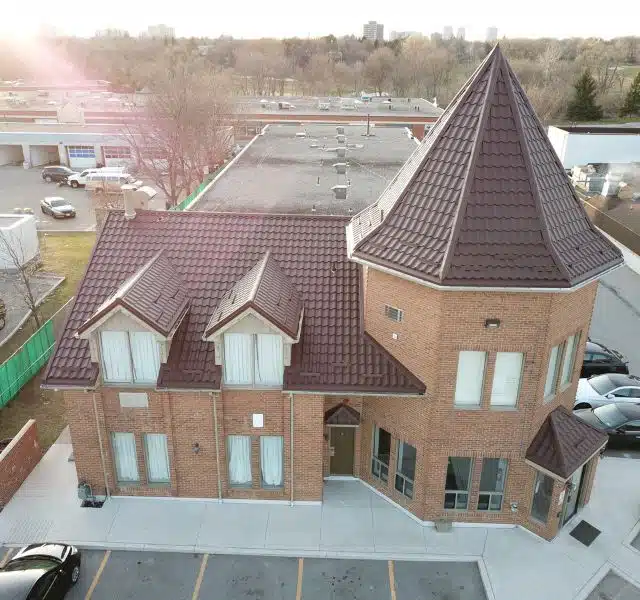 Brick commercial building with brown metal tile roofing and tower design.