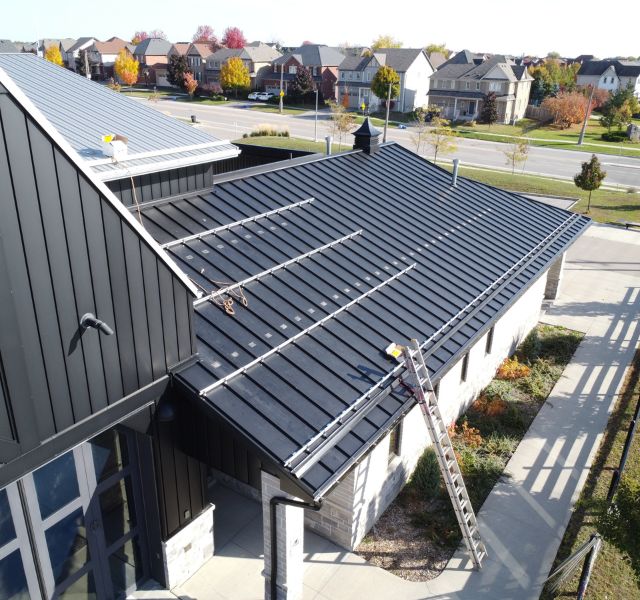 Black metal roof on a modern commercial building with safety rails installed.
