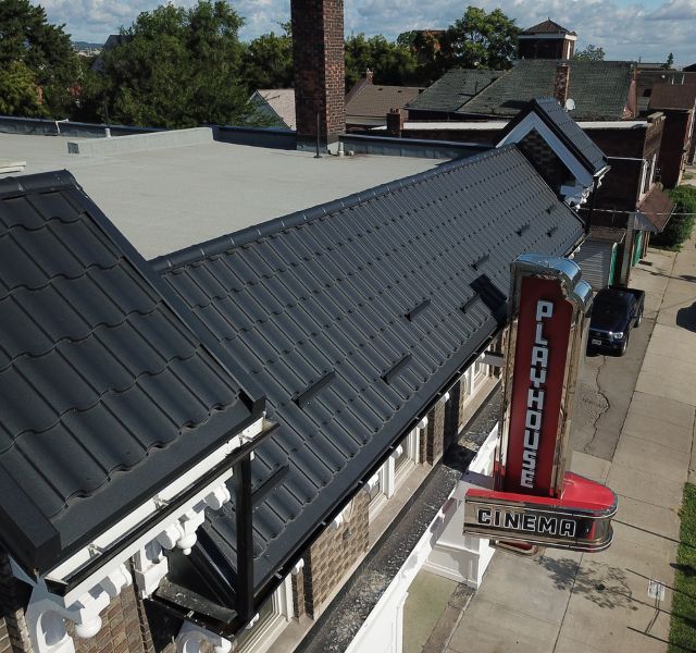 Commercial building with black metal roofing and Playhouse Cinema sign.