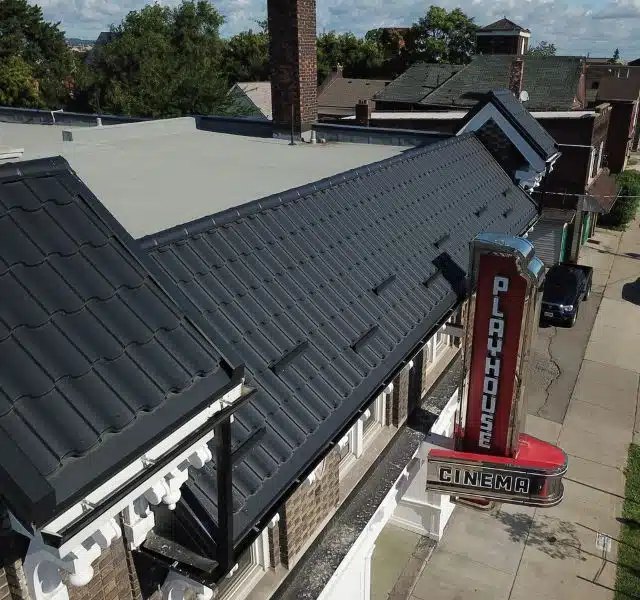 Commercial building with black metal roofing and Playhouse Cinema sign.