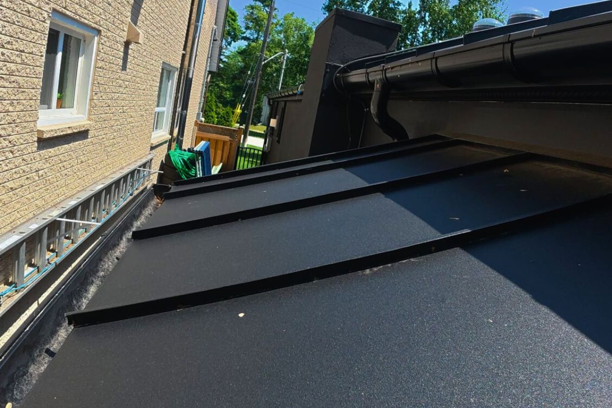 mississauga-black-standing-seam-roof Black standing seam metal roof with waterproof sealing next to brick wall in Mississauga