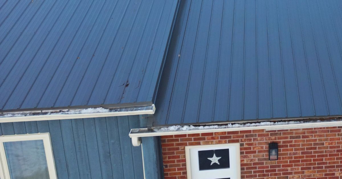 Ice and snow inside residential gutter system under metal roofing