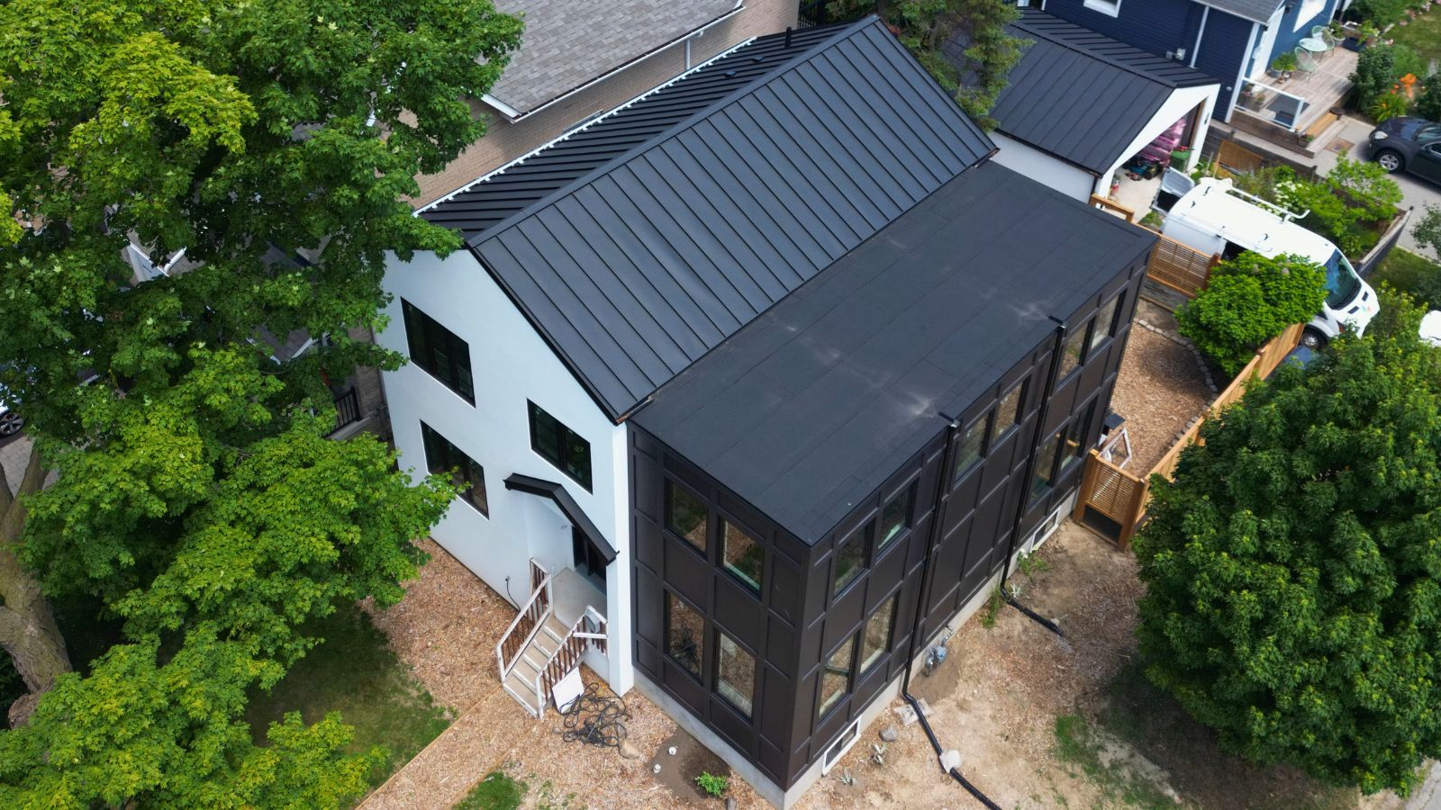 Standing seam metal roof on a residential home in Etobicoke with a flat roof section and dark metal finish
