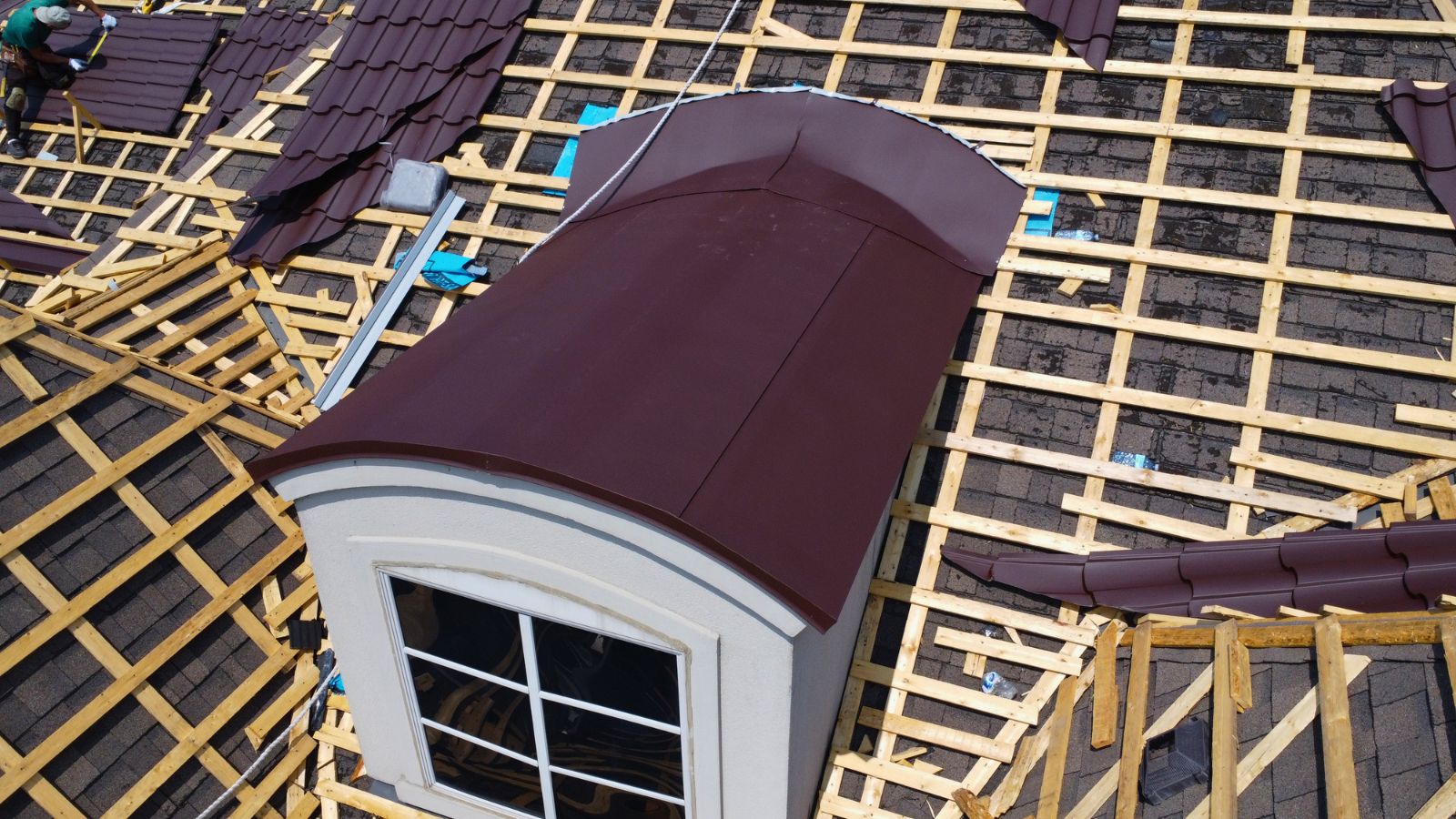 Curved dormer roof section with custom metal flashing during metal tile installation