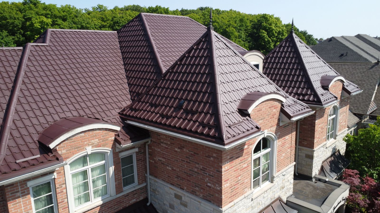 Brown metal tile roof with dormers, hips, roof vents, and front-facing roof sections