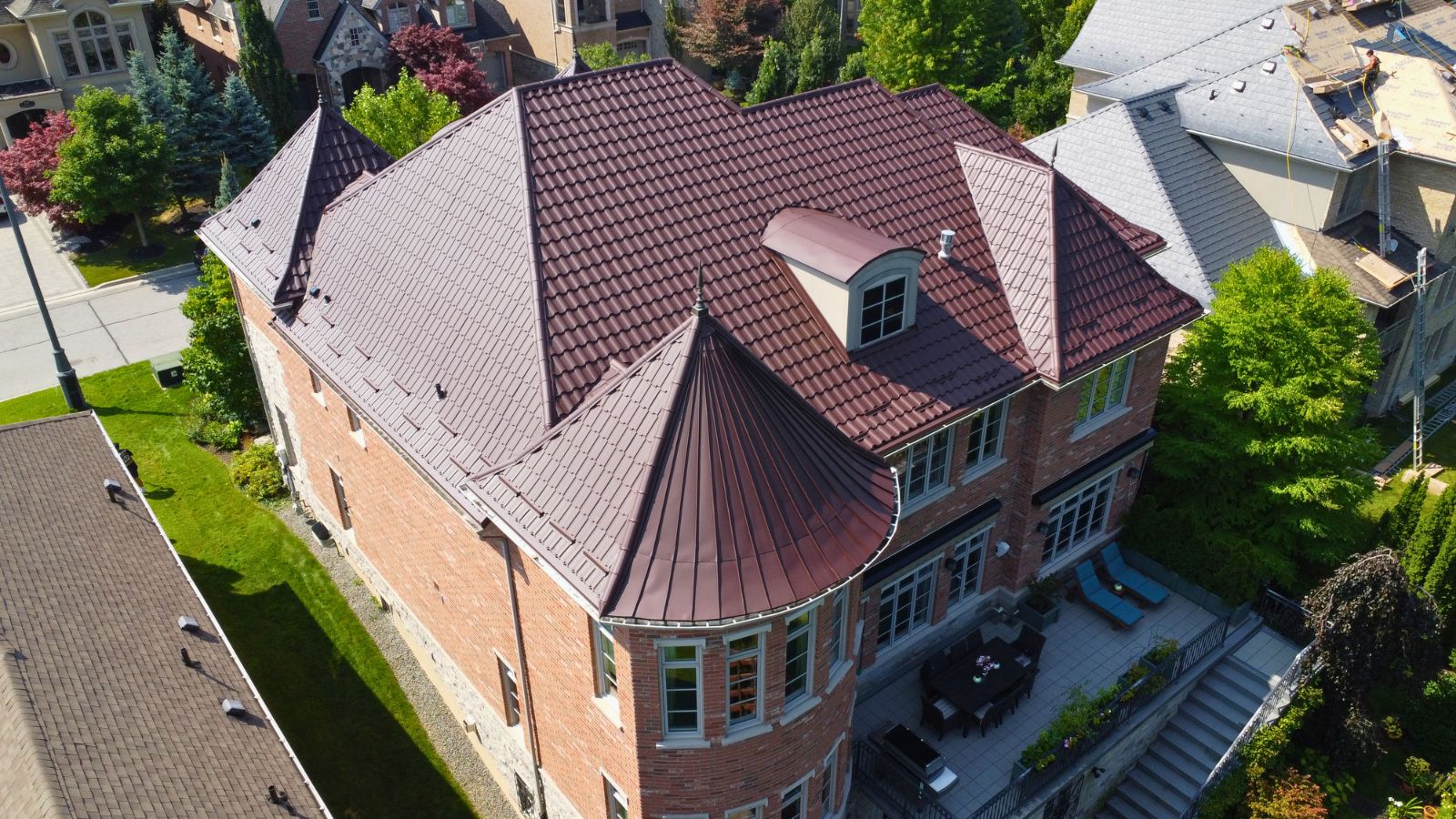 Metal tile roof with rounded turret section, dormer, vents, and multi-slope roof layout