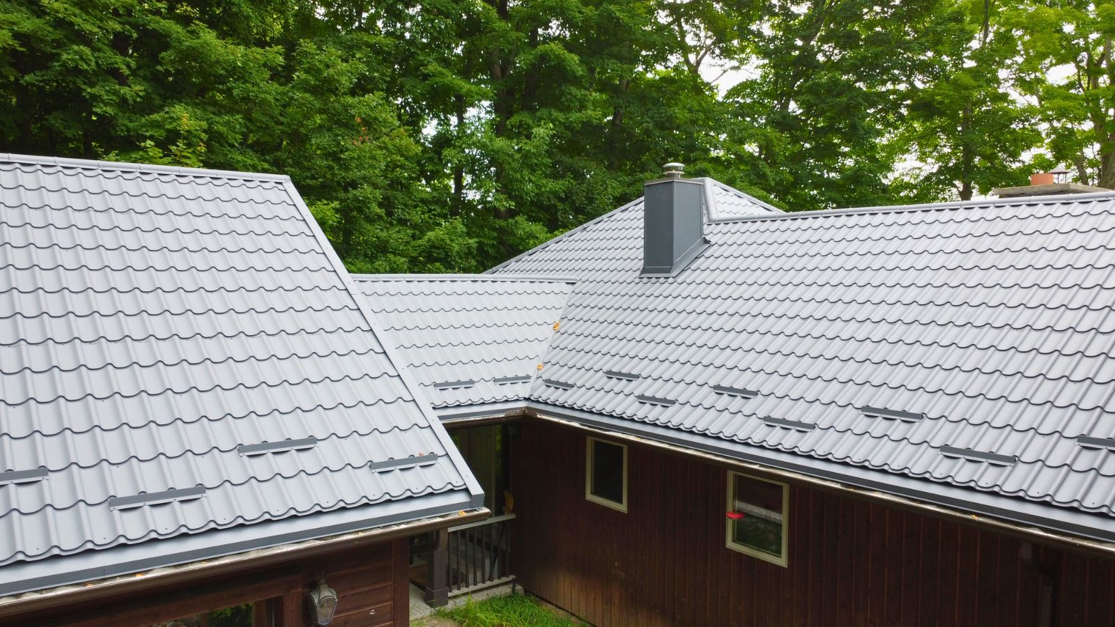 RR22 Grey metal tile roof with individual snow guards, roof vents, and multiple roof sections