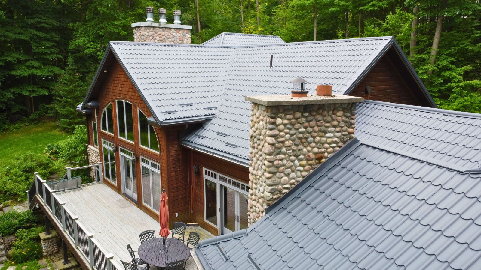 Metal tile roof in RR22 Grey with stone chimney details, roof valleys, and individual snow guards
