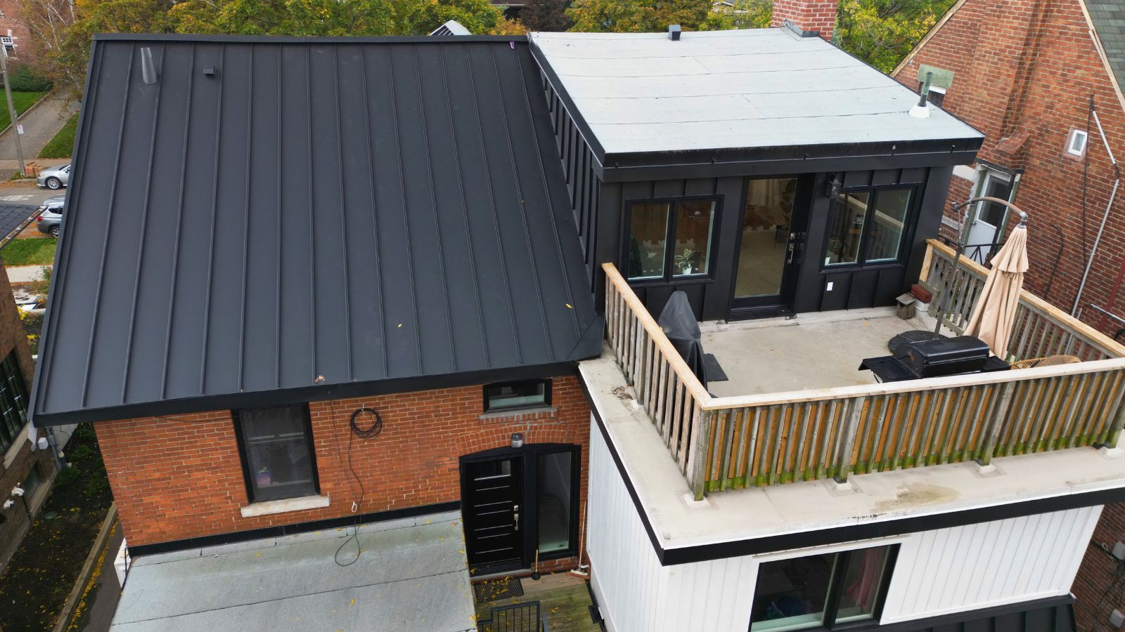 Rear exterior of a High Park home with standing seam roofing and a flat roof beside the terrace area