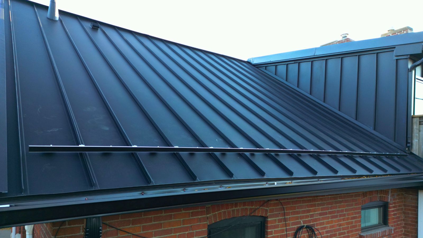 S-5 ColorGard snow retention installed across a black standing seam roof on a Toronto century home
