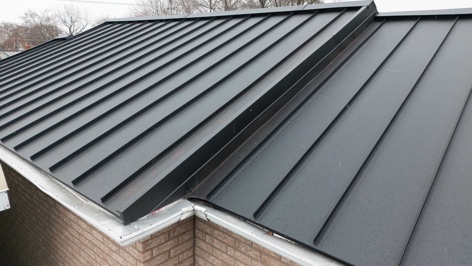 Metal valley detailing between adjoining standing seam roof sections