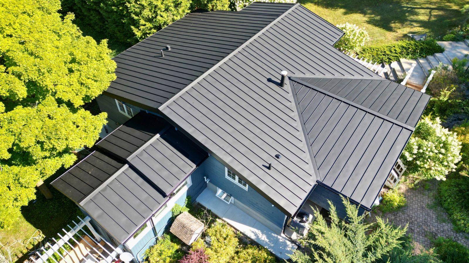 Aerial view of the completed Midnight Black mechanical-lock standing seam roof in Acton